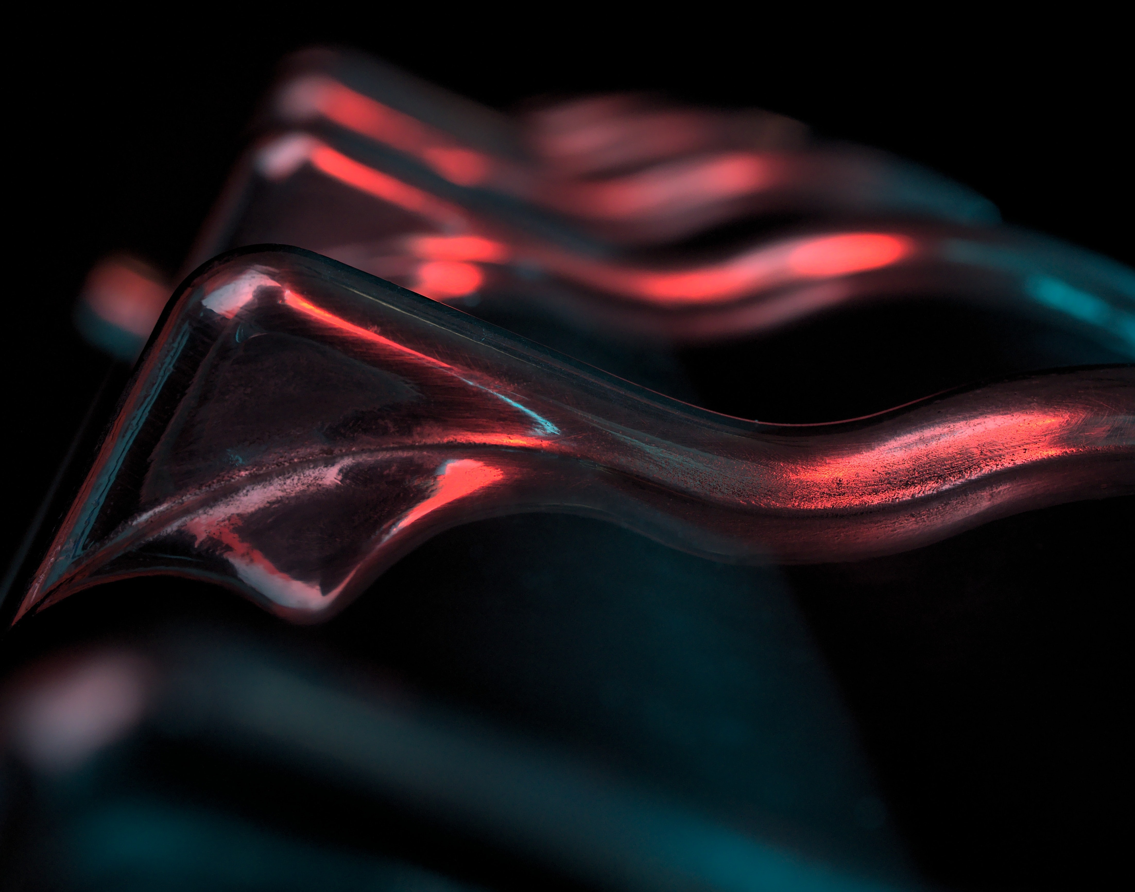 Abstract image of an object similar to waves lit by red and blue lights.
